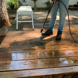 Pressure Washing A picture of someone pressure washing a deck before painting it.